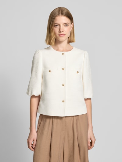 Modelka kobieca nosi Regular Fit Blazer aus Viskose-Mix mit Puffärmeln von More & More, kolor kremowy, struktura, okrągły dekolt, krótki rękaw, złote guziki, szerokość w rozmiarze 36: 44 cm, długość tyłu 46 cm, długość rękawa 35 cm, widok całej sylwetki z przodu.
