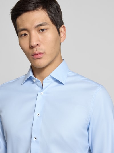 Männermodel trägt Slim Fit Business-Hemd mit Kentkragen von ETERNA aus reiner Baumwolle, hellblau, glatte Textur, Nahaufnahme Oberkörper.