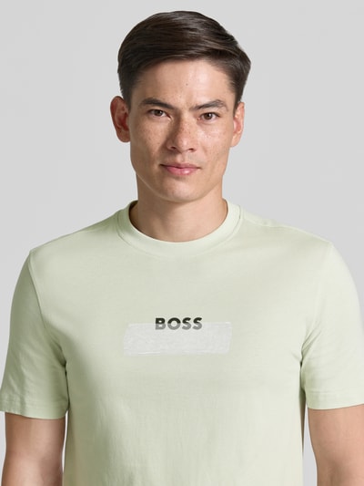 Męski model nosi Regular Fit T-Shirt aus reiner Baumwolle Modell 'Te_LOGOTAPE' von BOSS Orange, krój regular fit, kolor jednolity, nadruk z logo, okrągły dekolt, krótki rękaw, materiał jersey, bawełna, zbliżenie na górną część ciała.