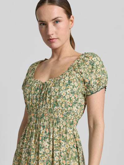 Frauenmodel trägt Midikleid aus Viskose mit Rüschenärmeln von Apricot, florales Muster, Taillierter Schnitt, Rundhalsausschnitt, Nahaufnahme Oberkörper. Rückenlänge bei Größe S: 113 cm, Brustweite: 29 cm, Ärmellänge: 16 cm, Smok-Detail.