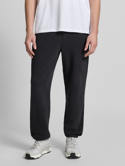 Männermodel trägt Sweatpants mit Eingrifftaschen Modell 'ATUBAY' von American Vintage, Baumwoll-Elasthan-Mix, Relaxed-Fit, elastischer Bund, Tunnelzug, schwarze Farbe, glatte Textur, Innenbeinlänge bei Größe M/L 77 cm, Ganzkörperansicht von vorne.