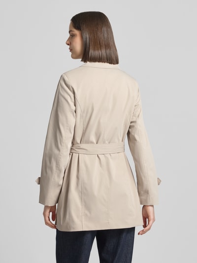 Kobiece model nosi trencz Regular Fit Trenchcoat mit Taillengürtel zum Binden Modell 'CHALSEA OLIVIA' von Vero Moda, efekt: jednolity kolor, krój regular fit, wykładany kołnierz, listwa guzikowa 2-rzędowa, szwy, długi rękaw z patkami na zakończeniu, boczne wpuszczane kieszenie, wykończenie materiału: splot twill; widok całej sylwetki z tyłu.