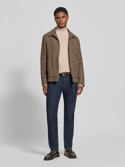 Männermodel trägt Wollpullover mit Rollkragen von Christian Berg Men in Beige, kombiniert mit Karojacke und Jeans, Ganzkörperansicht von vorne. Woll-Mix, gerader Schnitt, gerippte Abschlüsse, Rückenlänge bei Größe M: 72 cm, Ärmellänge bei Größe M: 70 cm.