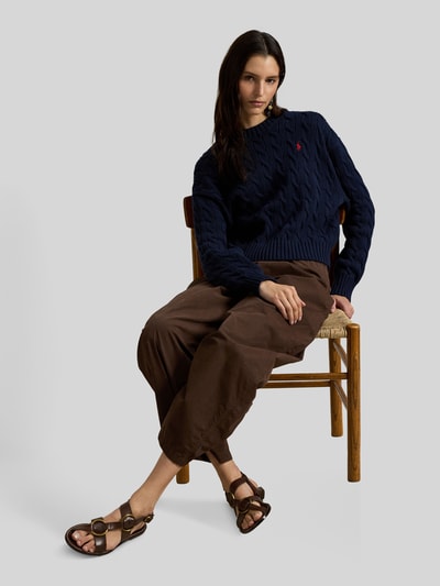Modelka kobieca ma na sobie Regular Fit Strickpullover aus reiner Baumwolle od Polo Ralph Lauren, granatowy, wzór warkoczowy, długi rękaw, dzianina bawełniana, aplikacja logo, ribb rand, widok całej sylwetki z przodu.