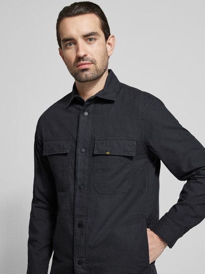 Männermodel trägt Regular Fit Hemdjacke aus reiner Baumwolle von camel active in Schwarz mit aufgesetzten Brusttaschen, Nahaufnahme Oberkörper.