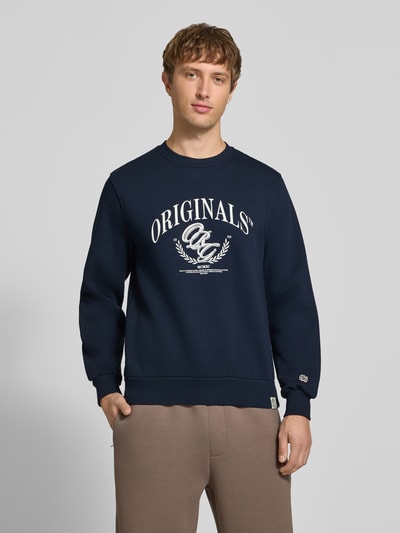 Männermodel trägt Sweatshirt mit Label-Print Modell 'FREDERIKSBERG' von JACK & JONES, dunkelblau, Baumwoll-Mix, Regular Fit, Nahaufnahme Oberkörper.