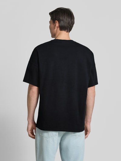 Männermodel trägt T-Shirt mit Rundhalsausschnitt Modell 'FIZVALLEY' von American Vintage in Schwarz, lockerer Schnitt, Ganzkörperansicht Rückansicht.