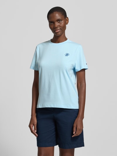 Vrouwenmodel draagt Regular Fit T-shirt uit katoenmix van Tommy Hilfiger in effen kleuren met gestikt logo, ronde hals, korte mouw, jersey, vooraanzicht heuphoogte.