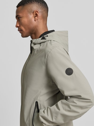 Mężczyznamodel nosi kurtkę Jacke mit Reißverschlusstaschen Modell 'MATTEO' von CARS JEANS z mieszanki materiałów z dodatkiem streczu, krój regular fit, kaptur z tunelem, zamek błyskawiczny, kieszenie zapinane na zamek błyskawiczny, kolor jasnoszary, faktura gładka, boczna perspektywa, zbliżenie na górną część ciała.