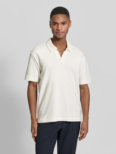 Männermodel trägt Relaxed Fit Poloshirt aus reiner Baumwolle von Marc O’Polo in offwhite mit Webstruktur, Label Patch, Ganzkörperansicht von vorne.