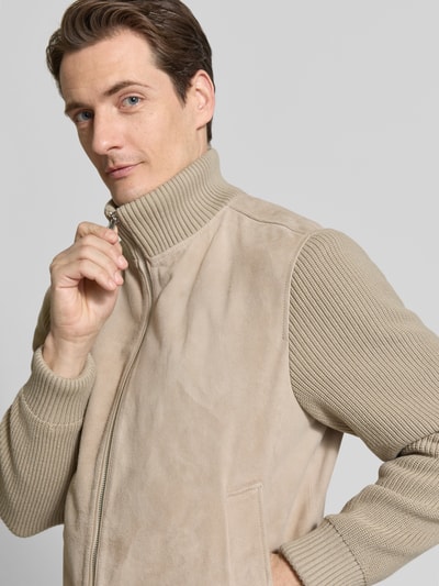 Männermodel trägt beige Jacke mit glatten und gerippten Flächen, Materialmix, Reißverschluss, Nahaufnahme Oberkörper.