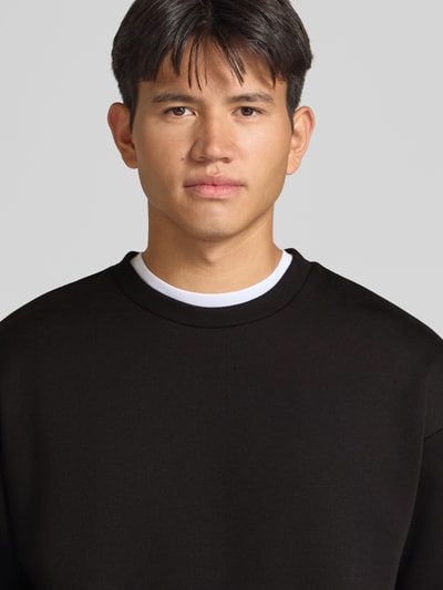 Männermodel trägt Regular Fit Sweatshirt mit Baumwoll-Anteil von JACK & JONES, Rundhalsausschnitt, Schwarz, Nahaufnahme Oberkörper.