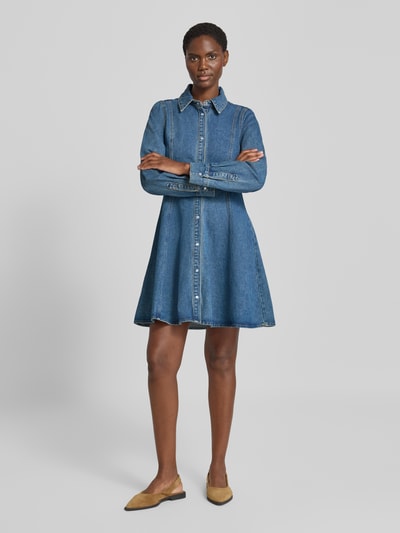 Frauenmodel trägt Tailliertes Freizeitkleid aus Baumwoll-Mix Modell 'JESSIE' von VERO MODA in Mittelblau mit Knopfleiste, strukturierter Jeansstoff, Ganzkörperansicht von vorne.