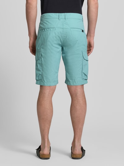 Männermodel trägt Bermudas mit Cargotaschen van camel active in lichtblauw, katoen, regular fit, cargozakken, labeldetail, Ganzkörperansicht Rückansicht.
