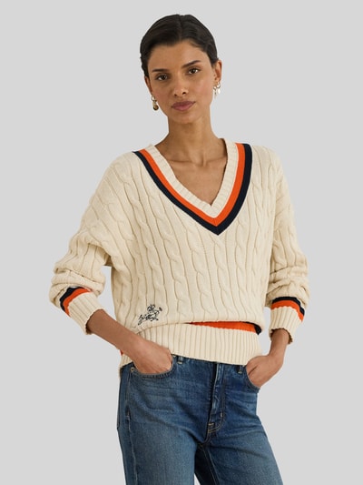 Frauenmodel trägt Regular Fit Strickpullover aus reiner Baumwolle von Lauren Ralph Lauren, Optik: Unifarben, Zopfmuster, Logo-Detail, Kontraststreifen, V-Ausschnitt, Langarm, gerippte Abschlüsse, Materialverarbeitung: Strick, Ganzkörperansicht von vorne.