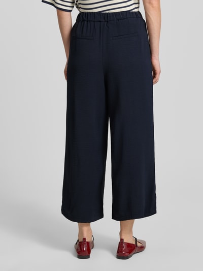 Vrouwenmodel draagt Wide Fit Stoffhose met bandplooien van Zero, donkerblauw, siergesp, verkorte pasvorm, deels elastische band, bandwijdte maat 36: 34 cm, binnenbeenlengte maat 36: 61 cm, geheel van achteren gezien.