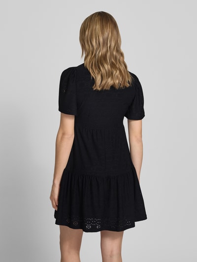 Modelka kobieca nosi czarną sukienkę Mini-Freizeitkleid mit Lochstickmuster Modell 'SMILLA LIFE' od Only, gładka optyka, krój regular fit, długość mini, dekolt w serek, ażurowy wzór, krótkie rękawy, szwy dzielące, całkowity widok z tyłu.