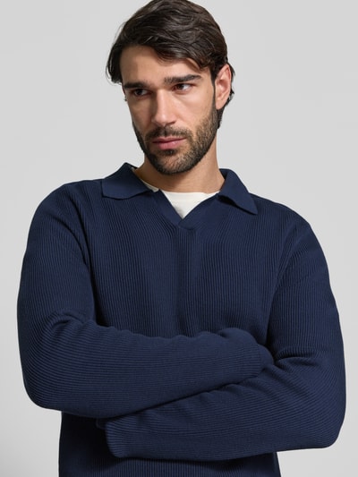 Männermodel trägt dunkelblauen Strickpullover aus reiner Baumwolle Modell 'NORDIN' von Casual Friday in Rippstrick-Optik, Nahaufnahme Oberkörper.