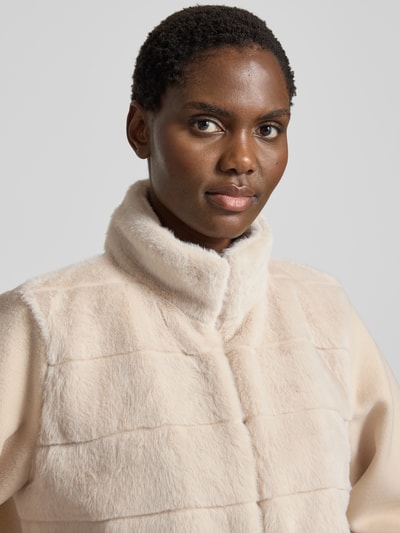 Frauenmodel trägt Jacke mit Viskose-Anteil Modell 'BALIA' von EMME in Beige mit Kunstfellbesatz und Steppnähten, Nahaufnahme Oberkörper.