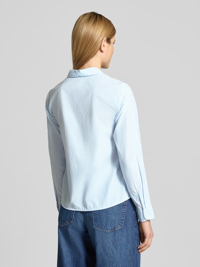 Frauenmodel trägt Regular Fit Hemdbluse mit Brusttasche Modell 'Darma' von Vila, Material-Mix mit Baumwoll-Anteil, Langärmelig, Hemdblusenkragen, durchgehende Knopfleiste, Sportmanschetten, Rückenlänge 62 cm, Ärmellänge 63 cm, hellblaue Farbe, glatte Textur, Ganzkörperansicht Rückansicht.