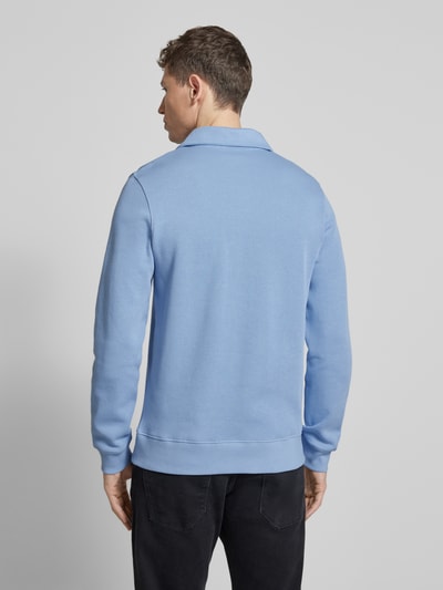 Männermodel trägt Regular Fit Sweatshirt aus reiner Baumwolle von Lacoste in Hellblau, unifarben, Polokragen, Rippmaterial, Ganzkörperansicht Rückansicht.
