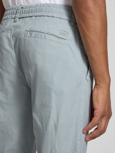 Mannenmodel draagt lichtblauwe tapered fit chino uit katoenmix model 'GABARDINE' van BOSS Orange, detailopname billen.
