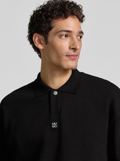 Męski model nosi Oversize Fit Sweatshirt aus Baumwoll-Mix Modell 'Dabins' von HUGO w kolorze czarnym, wyraźna tekstura, nahaufnahme górnej części ciała. Bluza męska od HUGO.