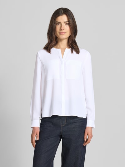 Frauenmodel trägt Regular Fit Bluse mit Brusttaschen von Marc Cain in Weiß, Tunika-Ausschnitt, langärmelig, glatte Oberfläche, Ganzkörperansicht von vorne.