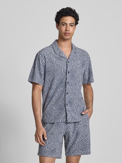 Mężczyzna model nosi Relaxed Fit Freizeithemd mit Baumwoll-Anteil Modell 'CLEMENT' od Only & Sons, niebiesko-białe faliste wzory, krótki rękaw, frotte, resortowy kołnierzyk, materiał z bawełną, całkowity widok z przodu.