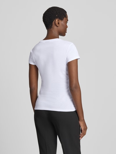 Frauenmodel trägt T-Shirt mit Ziersteinbesatz und Rundhalsausschnitt von Armani Exchange, weiße Baumwolle, Slim Fit, Rückenlänge 59 cm, Ganzkörperansicht Rückansicht.
