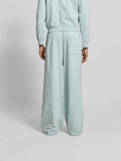 Männermodel trägt Wide Fit Sweatpants mit elastischem Bund von MM6 Maison Margiela in Hellblau, Gesäßtasche, Reine Baumwolle, Ganzkörperansicht Rückansicht.