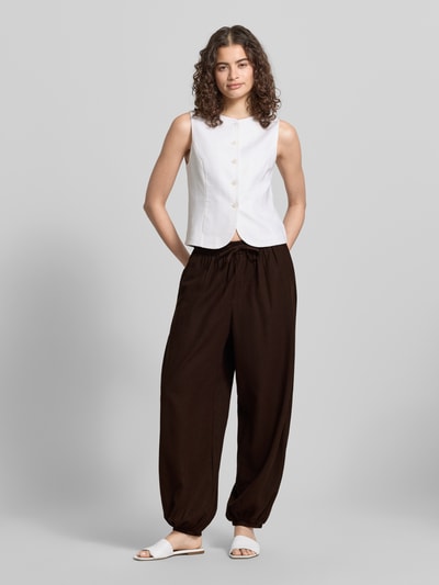 Frauenmodel trägt Regular Fit Weite Hose aus Viskose-Leinen-Mix Modell 'GOA' von Only in Optik: Unifarben mit Tunnelzug, Bundabschluss: elastisch, Beinabschluss: elastisch, seitliche Eingrifftaschen, Gesäßtasche, Materialverarbeitung: Flammgarn, Ganzkörperansicht von vorne.