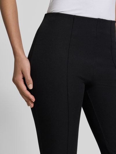 Frauenmodel trägt Flared Stoffhose mit Nahtreißverschluss von Jake*s Collection, schwarze Farbe, sichtbare Eingrifftaschen, Nahaufnahme Oberkörper.