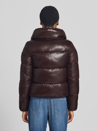Frauenmodel trägt Regular Fit Steppjacke mit Stehkragen Modell 'Isla' von Save The Duck, braun glänzende Oberfläche, Ganzkörperansicht Rückansicht.