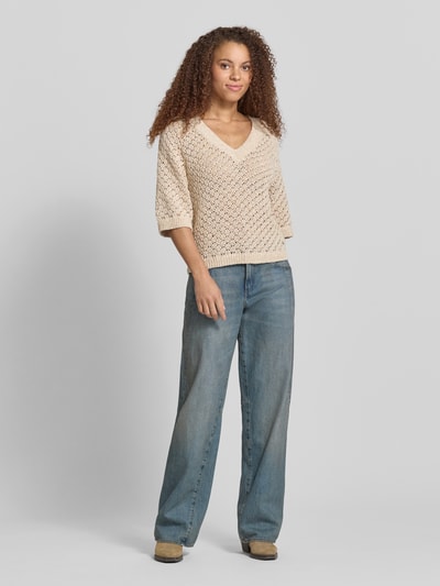 Modelka kobieca ma na sobie Boxy Fit Strickpullover aus Baumwoll-Mix Modell 'AMBER' od Pepe Jeans, imitacja dzianiny, ażurowa faktura, kremowy kolor, aplikacja z metką, krój pudełkowy, dekolt w serek, krótki rękaw, prążkowane wykończenia, mieszanka bawełny, całkowity widok z przodu.