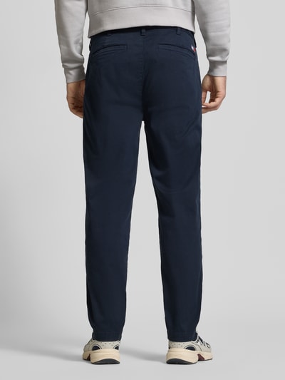 Männermodel trägt Tapered Chino aus Baumwoll-Mix Modell 'SONNY' von Tommy Jeans in Unifarben, Regular-Fit, Twill, Gesäßtaschen, Ganzkörperansicht Rückansicht.