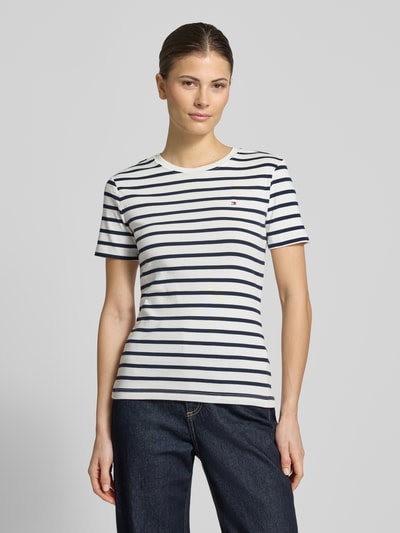 Frauenmodel trägt Slim Fit T-Shirt aus reiner Baumwolle von Tommy Hilfiger, unifarbenes Jersey mit Logo-Stitching, navy-weiß gestreift, Rundhals, Kurzarm, Ganzkörperansicht von vorne.