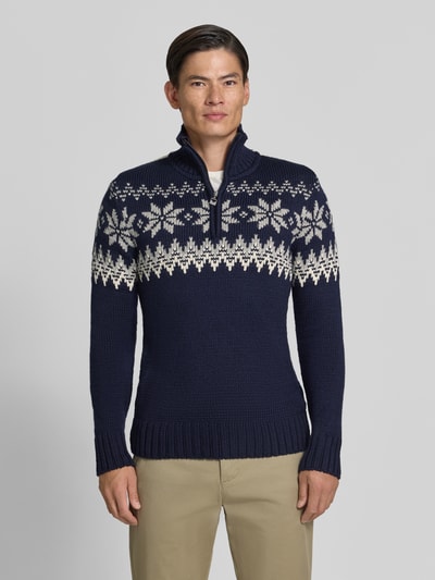Männermodel draagt Slim Fit pullover uit wolmix, Model 'Myking' van Dale of Norway met schipperskraag, Ruglengte maat M 72 cm, Mouwlengte 69 cm, heren pullover, donkerblauw met beige noors patroon, structuur van fijn breisel, Ganzkörperansicht von vorne.