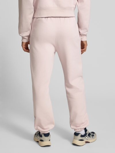 Männermodel trägt Sweatpants mit Label-Detail von Champion in Rosa, gerade geschnitten, mit Elastikbund, Ganzkörperansicht Rückansicht.