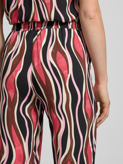 Frauenmodel trägt Straight Fit Stoffhose aus reiner Viskose Modell 'Cammi' von Soyaconcept mit mehrfarbigem Wellenmuster, elastischer Bund mit Tunnelzug, Detailaufnahme Rückansicht, Bundweite bei Größe S 35 cm, Innenbeinlänge 74 cm.