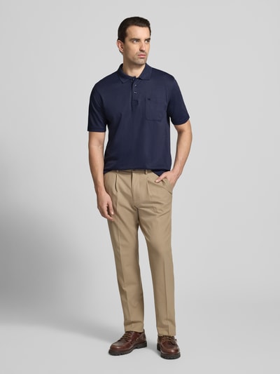 Męski model nosi Regular Fit Poloshirt mit Brusttasche od Christian Berg Men, ciemnogranatowy, kieszeń na piersi, mieszanka materiałowa z bawełną, kołnierzyk polo, guziki, krój regular fit, długość pleców w rozmiarze M: 68 cm, widok całej sylwetki z przodu