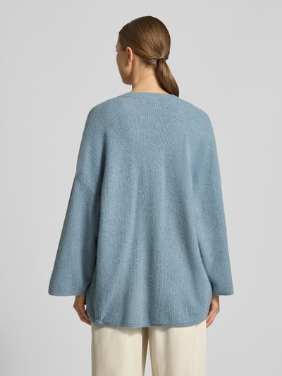 Frauenmodel trägt Relaxed Fit Cardigan mit Woll-Anteil Modell 'Damsville' von American Vintage in Strick-Optik, hellblau, Rückenansicht.