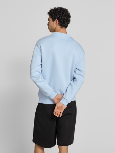 Mężczyznamodel nosi Sweatshirt mit Rundhalsausschnitt und Logo von REVIEW, mieszanka bawełny, krój regular fit, długość tyłu 70 cm, długość rękawów 62 cm, jasnoniebieska tkanina, prosty fason, faktura gładka, Ganzkörperansicht Rückansicht.