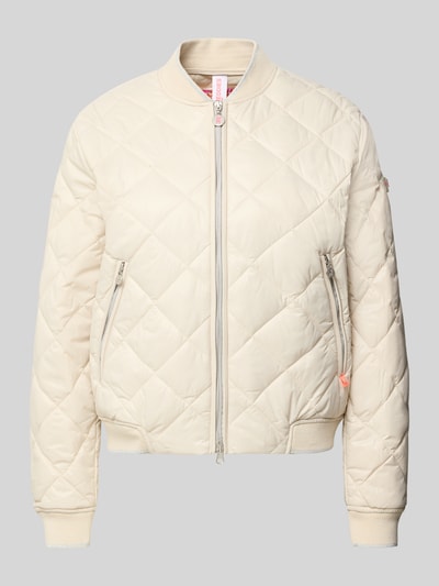 Frauenmodel trägt Steppjacke mit Zweiwege-Reißverschluss Modell 'BOY' von Frieda & Freddies in Beige, Regular Fit, Stehkragen, Reißverschlusstaschen, Ganzkörperansicht von vorne. Rückenlänge 20 cm, Schulterbreite 16 cm, Brustweite 21 cm, Ärmellänge 24 cm.