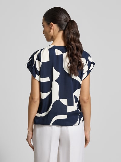 Frauenmodel trägt Regular Fit Bluse aus reiner Viskose Modell 'Miriama' von ZABAIONE mit abstraktem Muster, Ganzkörperansicht Rückansicht. Damen Bluse mit Tunika-Ausschnitt, kurzärmeligem Design und elastischem Bund, Rückenlänge bei Größe S 62 cm.