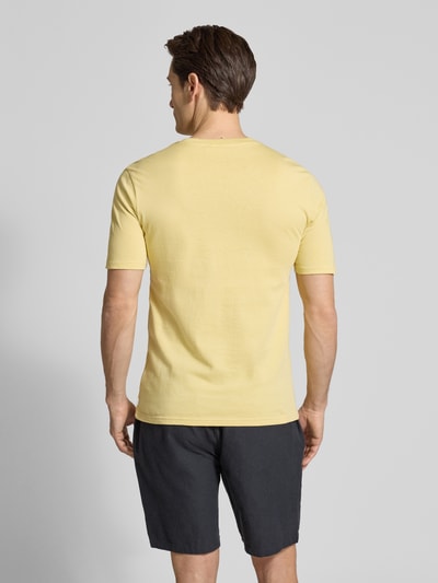 Męski model nosi T-shirt mit Rundhalsausschnitt von Scotch & Soda z bawełny, krój regular fit, nadruk z logo, długość tyłu 68 cm, jasny żółty, widok całej sylwetki z tyłu.