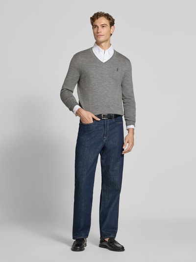 Männermodel trägt Regular Fit Pullover aus reiner Wolle von Polo Ralph Lauren in Grau, kombiniert mit Hemd und Jeans, Ganzkörperansicht von vorne.