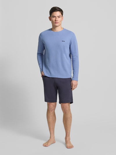 Męski model nosi Regular Fit Langarmshirt aus Baumwoll-Mix od BOSS, kolor niebieski, faktura waflowa, okrągły dekolt, widok całej sylwetki z przodu.