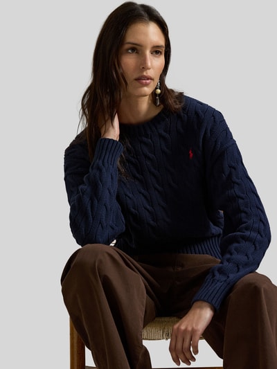 Modelka nosi Regular Fit Strickpullover aus reiner Baumwolle od Polo Ralph Lauren, granatowy, wzór warkoczowy, logo, ściągacze, widok z przodu, półzbliżenie.