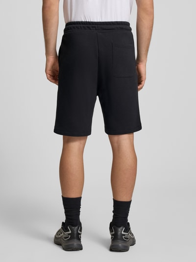 Männermodel trägt zwarte Sweatshorts met logo Model 'KANE' van Jack & Jones, katoenmix, relaxed fit, elastische tailleband, detailopname rugaanzicht.